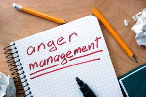 Notepad with anger management on office wooden table.