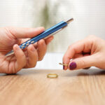 Husband is giving pen to sign divorce papers his former wife after he take off the ring form finger
