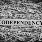 Torn pieces of paper with the words Codependency