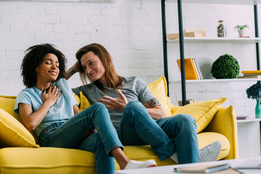 Young couple talking with gestures on sofa at home