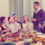 Multigenerational cheerful family sitting at festive table near Christmas tree