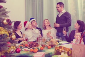 Multigenerational cheerful family sitting at festive table near Christmas tree