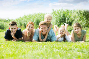 Glad man and woman with four kids lying in park on summer day