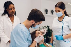 Woman patient smiling and receiving treatment from professional dentist doctor for an oral care check up about cavities and gum disease in a dental clinic.
